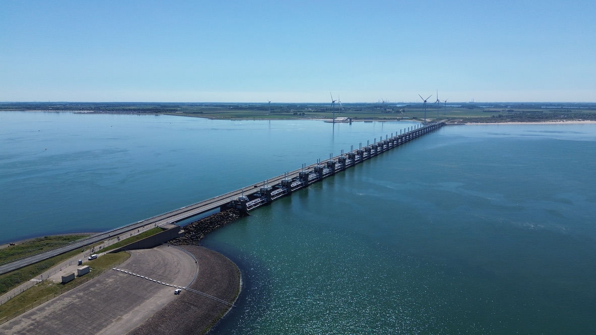 Luchtbeeld van een lange waterkering over helderblauw water